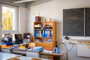 A classroom with supplies, desk, and a chalkboard